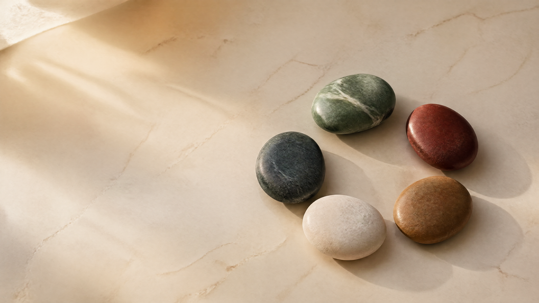 Five natural stones representing Wood, Fire, Earth, Metal and Water beside an open journal