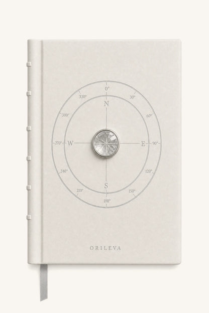 The Luminous Journal — pale leather cover with compass linework and natural clear quartz inlay
